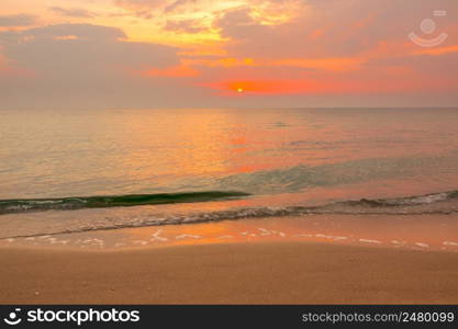 Orange sunset over the calm sea. Green wave runs onto a sandy beach. Orange Sunset over Green Wave