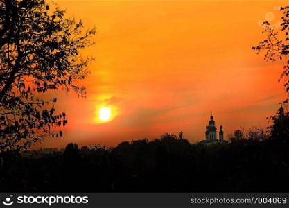 Orange sunset with beautiful evening landscape. Panorama with silhouettes of branch of trees and church on background of beautiful decline. Twilight with bright sunset. Bright landscape over city. Orange sunset with beautiful evening landscape. Twilight with bright sunset.