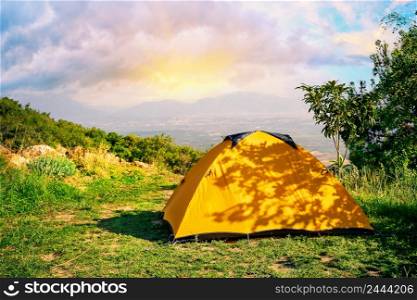 Orange tent on a hill with mountains in the background at sunrise. Orange tent on hill with mountains in background at sunrise