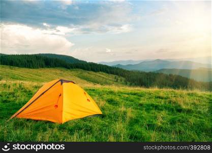 Orange tourist tent in the mountains under the bright sun. Orange tourist tent in the mountains under bright sun