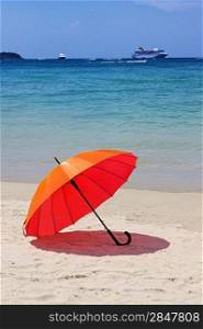 orange umbrella at the beach with a turquoise sea