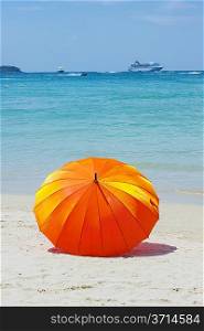 orange umbrella at the beach with a turquoise sea