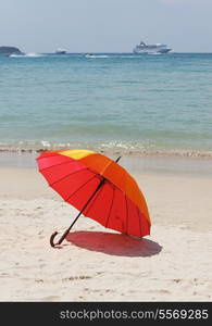 orange umbrella at the beach with a turquoise sea