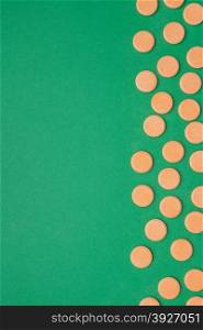 orange vitamin pills on a green background