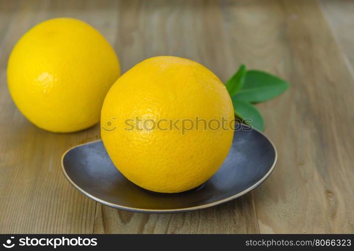 orange with leaves on dish . ripe orange with leaves on dish over wooden background