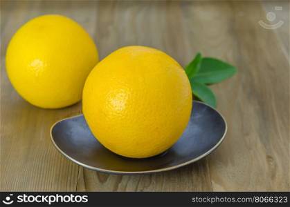 orange with leaves on dish . ripe orange with leaves on dish over wooden background