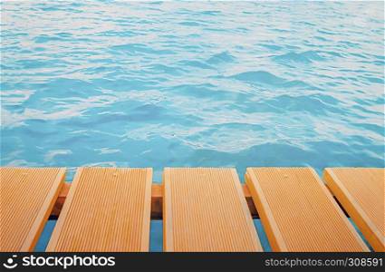 Orange wooden planks of pier closeup over blue water ripple - background with space for copy.. Pier Planks Over Sea Background