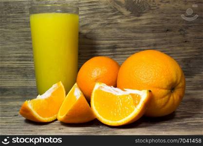 Oranges and fresh orange juice on wooden background