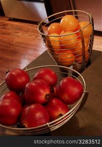 Oranges and pomegranates in kitchen baskets.