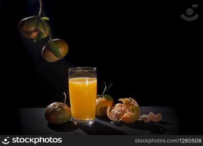 oranges tangerine and glass,citrus reticula.on table with black background and back light still life .mandarin variety orange contains pomelo and c vitamin.