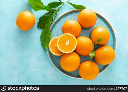 Oranges with leaves on blue background, top view