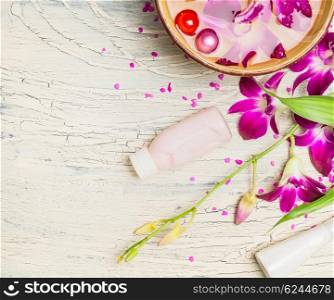 Orchid , cream and lotion with water bowl on white shabby chic background, top view. Spa or wellness concept