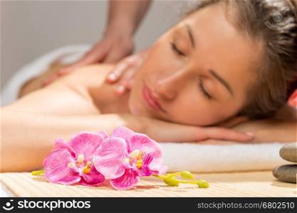 orchid on a massage table in the spa cabinet and a woman's face