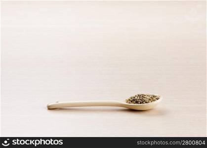 Oregano in a spoon over a blured wooden background with copy space
