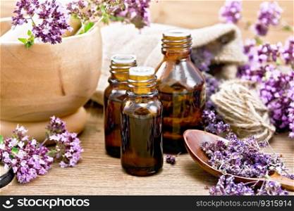 Oregano oil in three vials, fresh and dried oregano flowers in a spoon, mortar, bag and on the table against the background of a wooden board