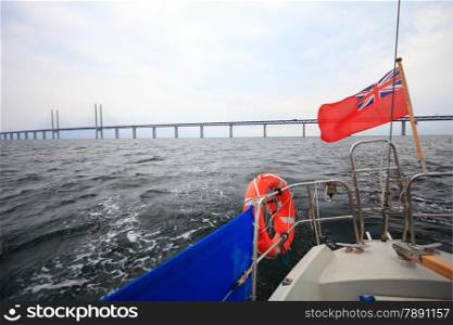 Oresundsbron. The Oresund bridge link between Denmark and Sweden, Europe, Baltic Sea. View from sailboat under UK british ensign. Overcast stormy sky.