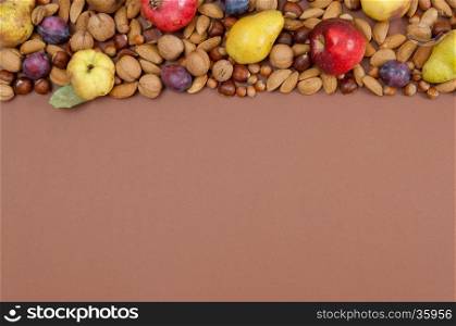 Organic autumn fruits and nuts on brown background with copy space