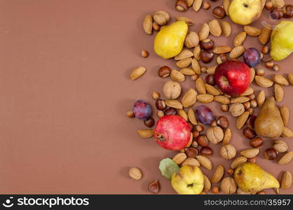 Organic autumn fruits and nuts on brown background with copy space