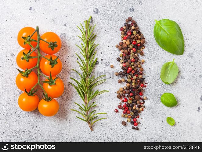 Organic Cherry Orange Rapture Tomatoes on the Vine with basil and pepper on white kitchen stone background