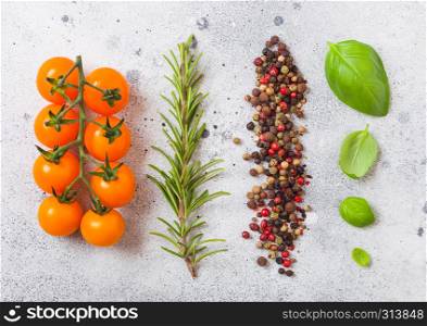 Organic Cherry Orange Rapture Tomatoes on the Vine with basil and pepper on white kitchen stone background