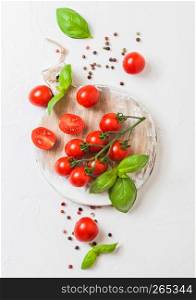 Organic Cherry Sugardrop Tomatoes on the Vine with basil and pepper on chopping board on stone background.