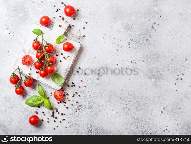 Organic Cherry Sugardrop Tomatoes on the Vine with basil and pepper on chopping board on stone background.