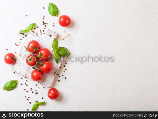 Organic Cherry Sugardrop Tomatoes on the Vine with basil and pepper on chopping board on stone background.