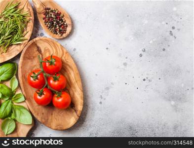 Organic Cherry Sugardrop Tomatoes on the Vine with basil in oilve wood plate and spoon with pepper on white background. Space for text