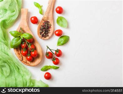 Organic Cherry Sugardrop Tomatoes on the Vine with basil in oilve wood plate and spoon with pepper on white background. Space for text