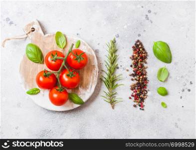 Organic Cherry Tomatoes on the Vine with basil and pepper on white kitchen stone background