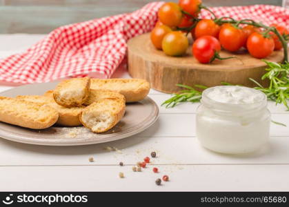 Organic cherry tomatoes with rosemary, swedish toasts and cream cheese on rustic wooden table