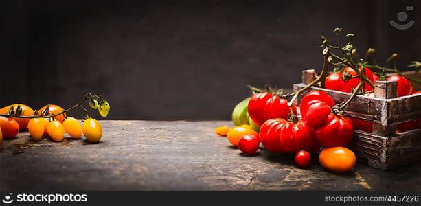 Organic colorful tomatoes in vintage box on rustic table over dark wooden background, banner for website