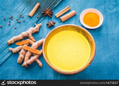 Organic curcumin honey golden milk, Indian turmeric latte with ingredients on bright blue background. Top view exotic spices yellow natural drink healthy food concept