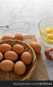 Organic eggs on sack cloth, many eggs on wicker basket and glasses bowl, oil and egg whisk placed on the floor, preparing for cooking food or dessert, copy    space