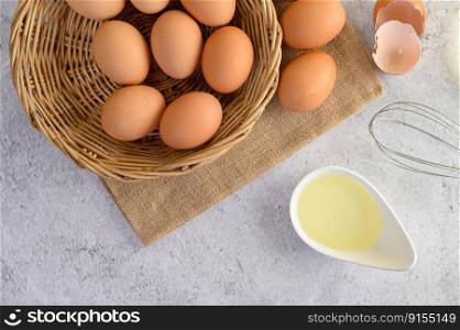 Organic eggs on sack cloth, many eggs on wicker basket and glasses bowl, oil and egg whisk placed on the floor, preparing for cooking food or dessert, copy 


space
