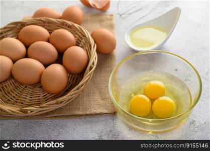 Organic eggs on sack cloth, many eggs on wicker basket and yolk glasses bowl, oil and egg whisk placed on the floor, preparing for cooking food or dessert, copy space