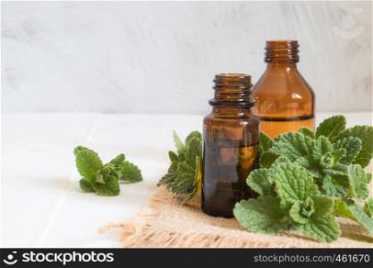 Organic essential oil of mint in a small glass jar with green leaves. Natural essential oil of mint.. Organic essential oil of mint in a small glass jar with green leaves. Natural oil of mint.