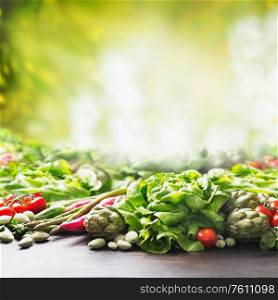Organic farm vegetables background at sunny summer garden green nature background. Eco veggies . Healthy clean food concept. Tomato, lettuce, root vegetables,artichokes, asparagus,herbs,carrots