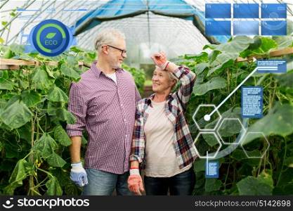 organic farming, agriculture and people concept - happy senior couple at farm greenhouse. happy senior couple at farm greenhouse