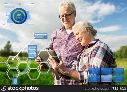 organic farming, agriculture and people concept - happy senior couple with tablet pc computer at summer farm. happy senior couple with tablet pc at summer farm