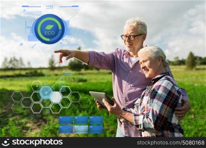 organic farming, gardening, agriculture and people concept - happy senior couple with tablet pc computer at summer farm. happy senior couple with tablet pc at summer farm