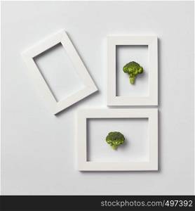 Organic frames with fresh natural broccoli and one empty frame on a light gray background, place for text. Flat lay. Vegetarian concept.. Creative pattern of frames with natural organic broccoli on a light background.