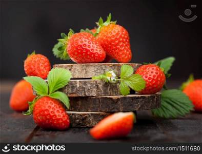 Organic fresh raw strawberries with leaf on timber round boards on dark background. Best summer berries.