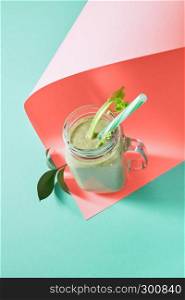 Organic freshly picked vegetables mixing healthy vegetarian smoothie in a glass mason jar on a color background of the year 2019 Living Coral Pantone, copy space. Flat lay.. Homemade fresh smoothies with avocado, selery, cucumber on a color background of the year 2019 Living Coral Pantone, copy space. Flat lay.