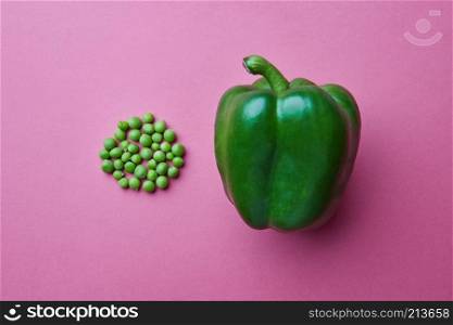 organic green bell pepper and green peas in the form of a circle isolated on a pink background. Clean eating concept.. Fresh green bell pepper and green peas on a pink background