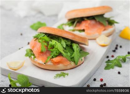 Organic healthy sandwiches with salmon and bagel, cream cheese and wild rocket and lemon and pepper on light.
