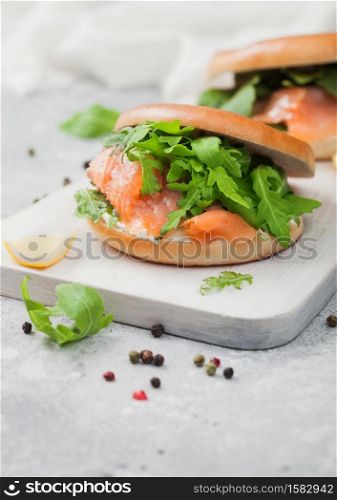 Organic healthy sandwiches with salmon and bagel, cream cheese and wild rocket and lemon and pepper on light.