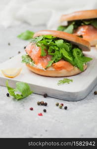 Organic healthy sandwiches with salmon and bagel, cream cheese and wild rocket and lemon and pepper on light.