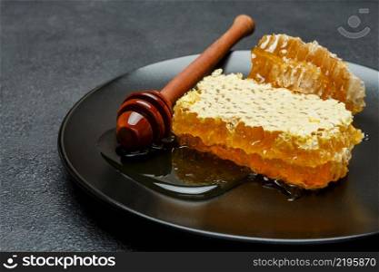 Organic Honeycomb with honey on plate. dark concrete background. Honeycomb with honey on plate. dark concrete background
