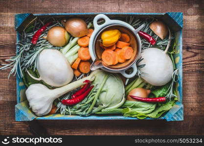 Organic local vegetables box for healthy clean eating and cooking on rustic wooden background, top view. Vegan or vegetarian food concept